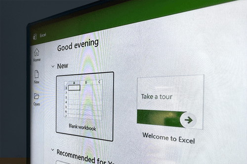 Close-up of a computer screen displaying the Microsoft Excel start page, with options for creating a new blank workbook and a “Take a tour” panel, along with navigation items like Home, New, and Open visible on the left sidebar.