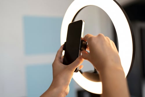 hands-placing-smartphone-into-ring-light