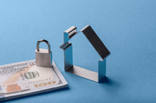 image_stack-of-100-dollar-bills-and-lock-next-to-small-metal-house