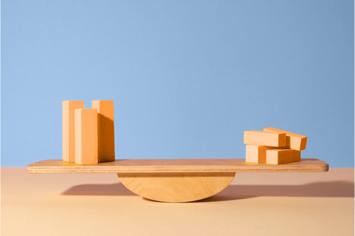 image_wooden-blocks-balanced-on-seesaw-against-blue-background