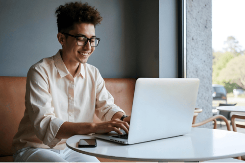 image_young-person-smiling-while-using-laptop-bright-cafe-setting